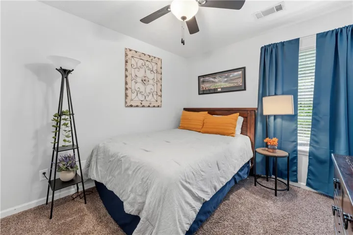 This cozy bedroom features a ceiling fan, plush carpeting, and a wooden headboard, creating a comfortable retreat.