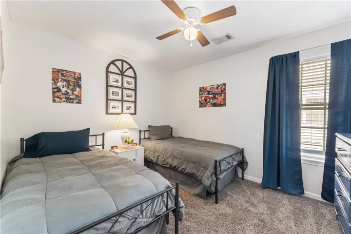 This cozy bedroom features comfortable beds, soft carpet, and a ceiling fan for year-round comfort.