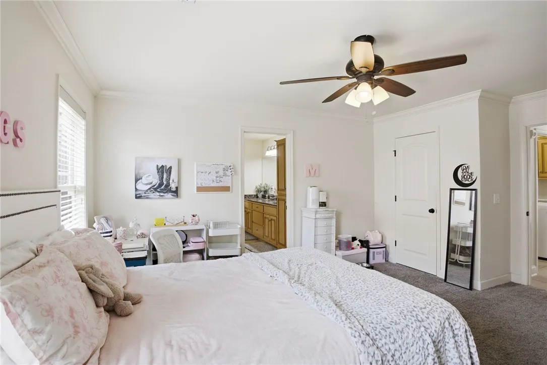 This spacious bedroom offers ample comfort, featuring a window for natural light and a convenient ceiling fan.