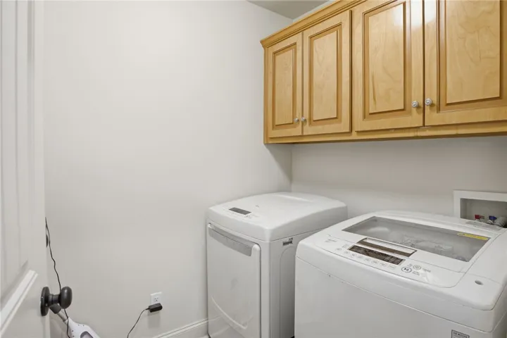 Functional laundry space featuring modern appliances and convenient overhead storage.
