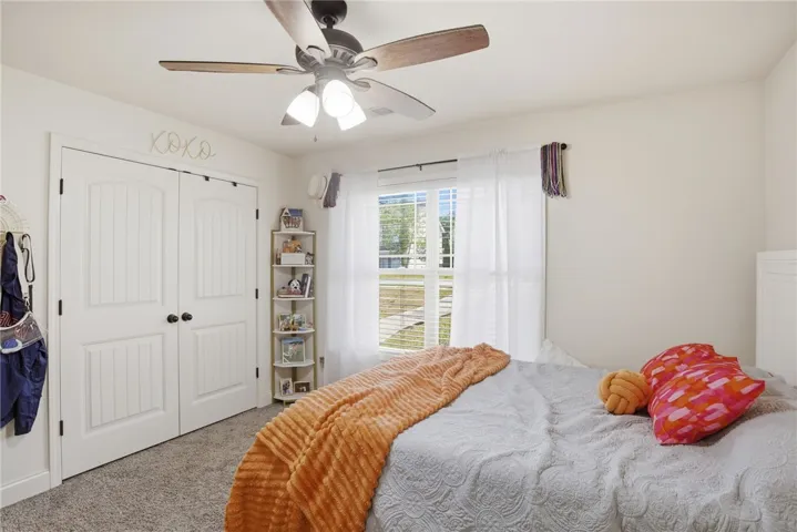 This cozy bedroom offers a tranquil retreat with soft carpet flooring and abundant natural light.