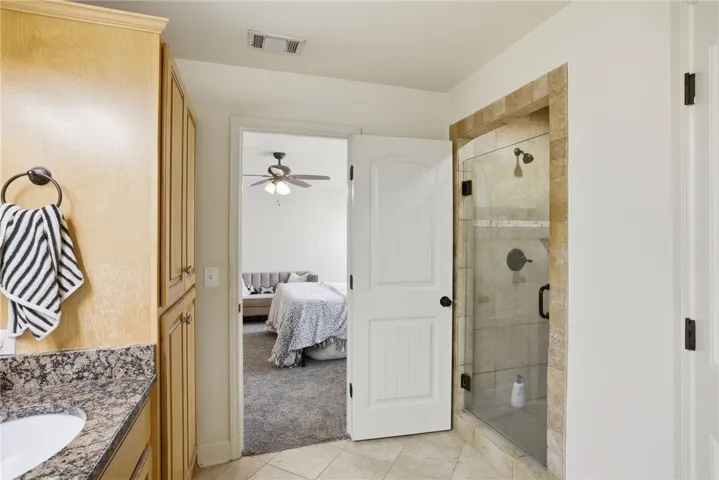 This primary bathroom offers a convenient layout with direct access to a carpeted bedroom.