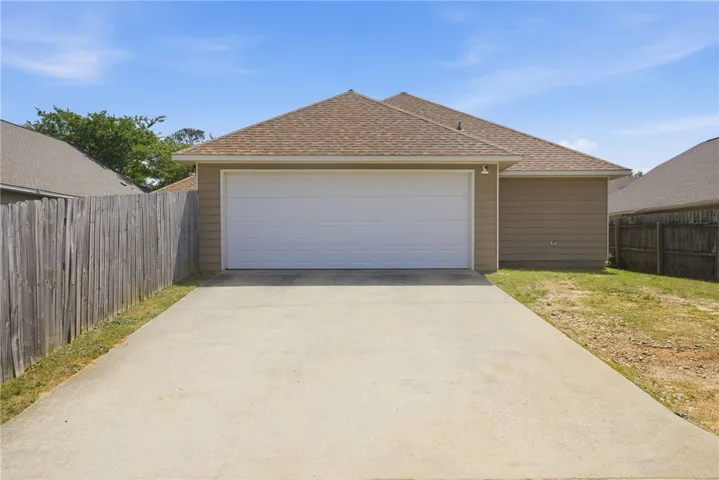 This residence features an attached garage with a concrete driveway, ensuring convenient parking and access.