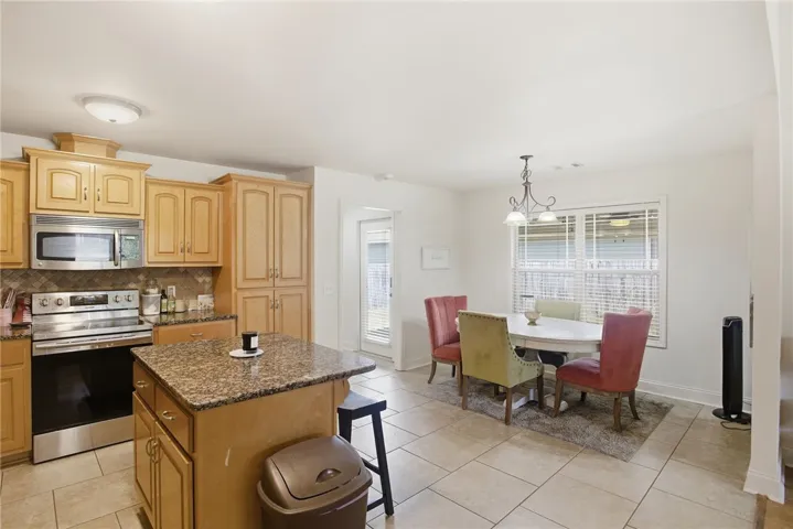 This spacious kitchen and dining area features natural wood cabinetry and ample room for daily meals.
