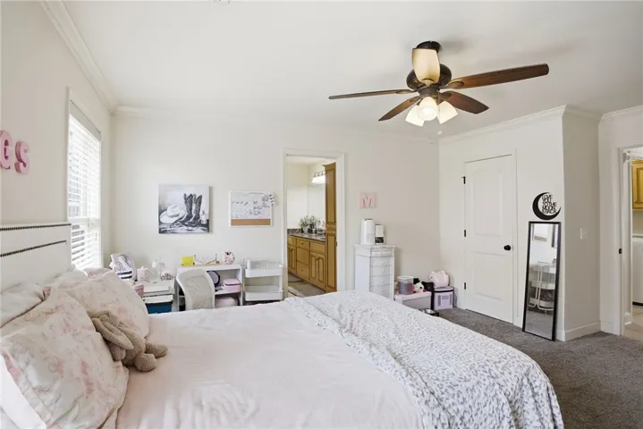 This spacious bedroom offers ample comfort, featuring a window for natural light and a convenient ceiling fan.