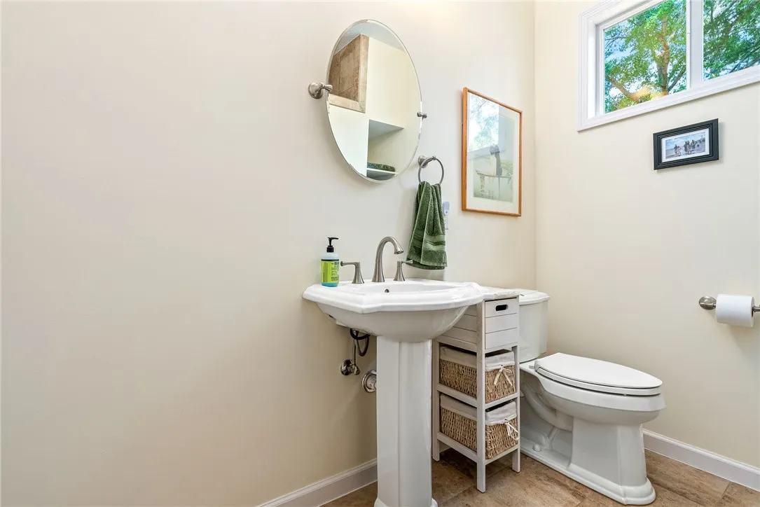 This bright bathroom features a pedestal sink and window for natural light.
