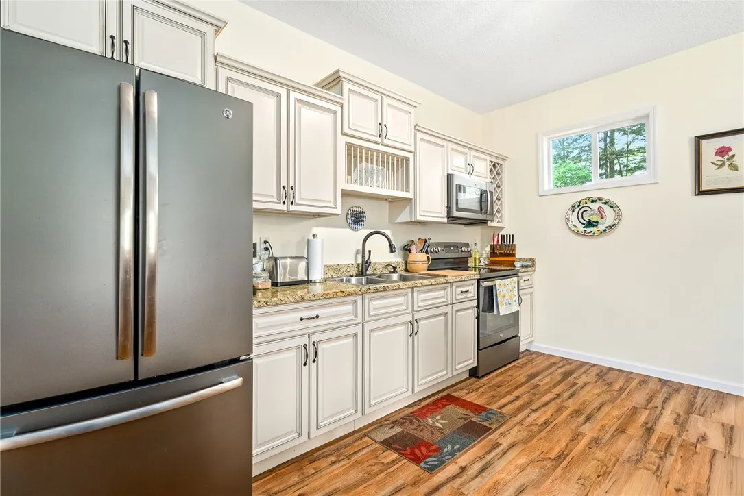 This bright kitchen features wood flooring and light cabinetry, creating a warm and inviting atmosphere.