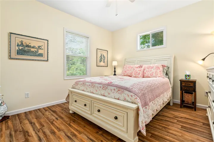 This tranquil bedroom features warm wood flooring and ample natural light, creating a serene personal retreat.