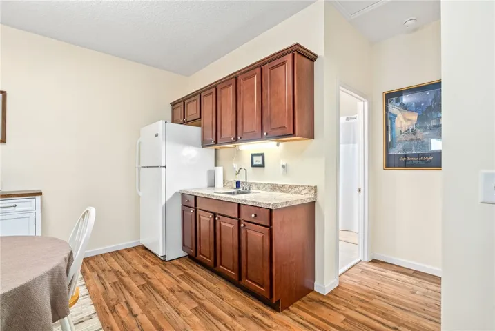 This kitchen boasts warm cabinetry, practical appliances, and durable flooring.
