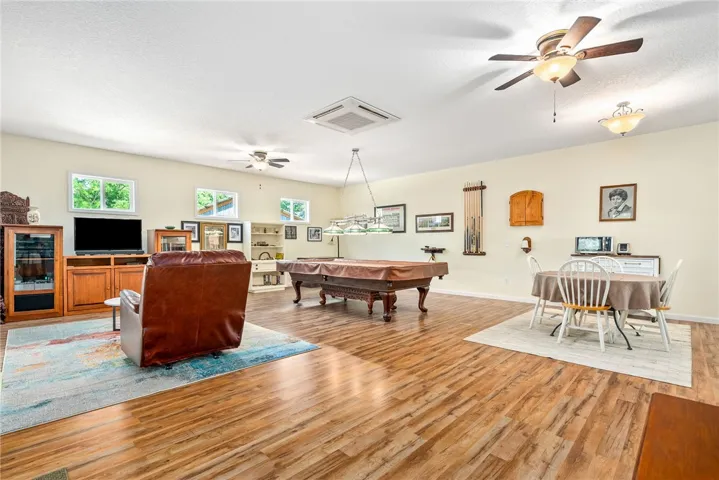 This spacious entertainment area features warm wood flooring, offering an inviting atmosphere for recreation.