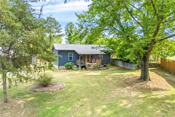 This charming home offers a tranquil escape amidst lush greenery and a spacious yard.