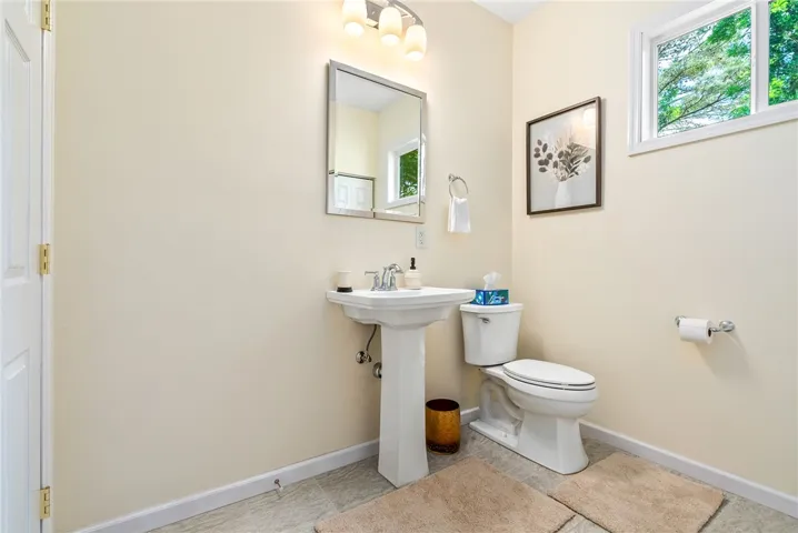 This bright bathroom features a pedestal sink and toilet, offering clean lines and functional design.