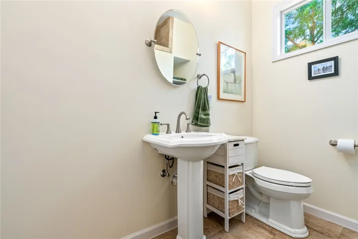 This bright bathroom features a pedestal sink and window for natural light.
