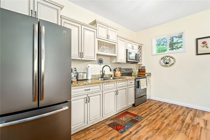 This bright kitchen features wood flooring and light cabinetry, creating a warm and inviting atmosphere.