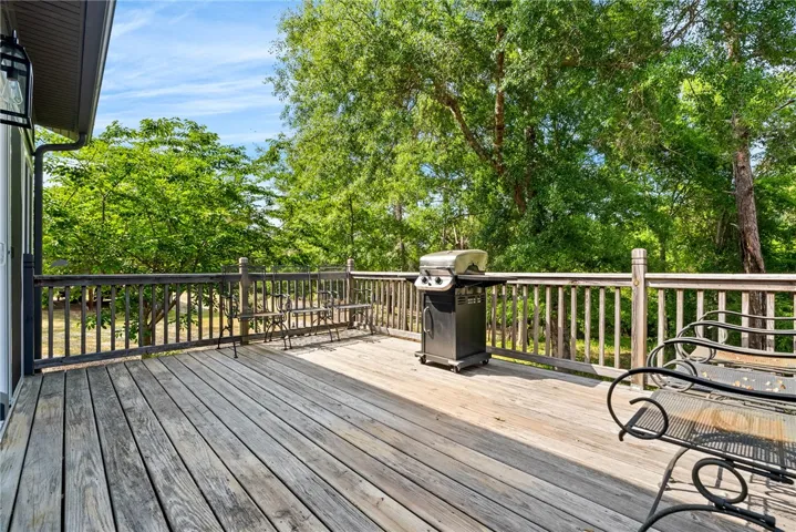 This spacious deck offers a tranquil retreat surrounded by lush greenery, perfect for outdoor enjoyment.