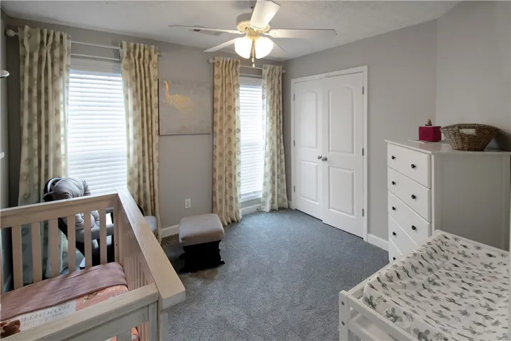 This cozy bedroom features a ceiling fan, closet, and carpeted floor.