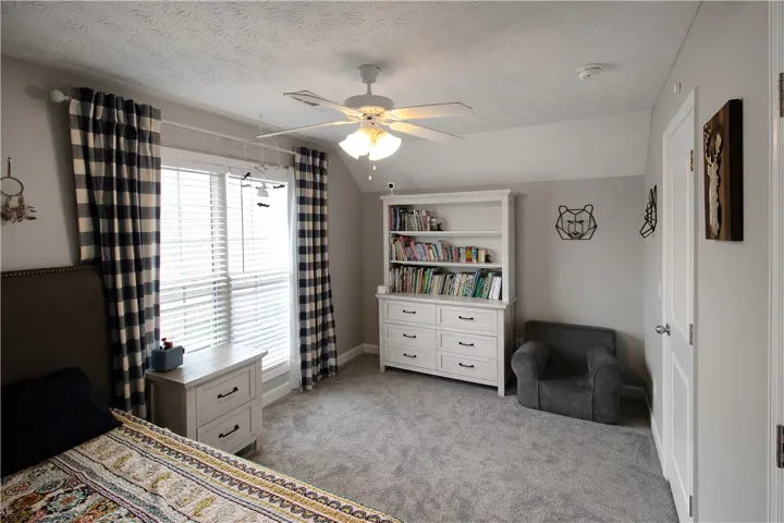 This cozy bedroom features a practical layout with carpeted floors and bright window.