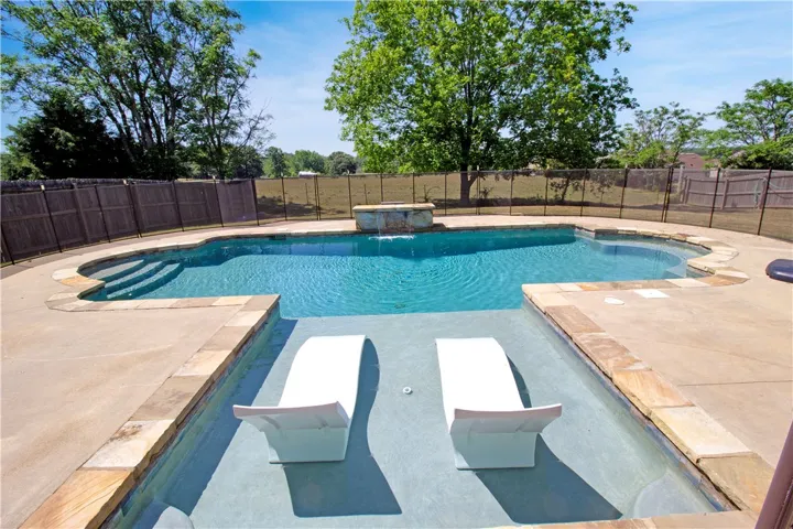 Relax poolside in this private oasis, featuring a beautiful in-ground pool with a waterfall.