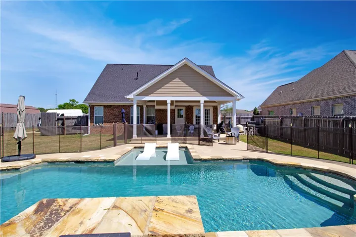 This spacious property offers a refreshing pool and an inviting covered patio, perfect for outdoor enjoyment.
