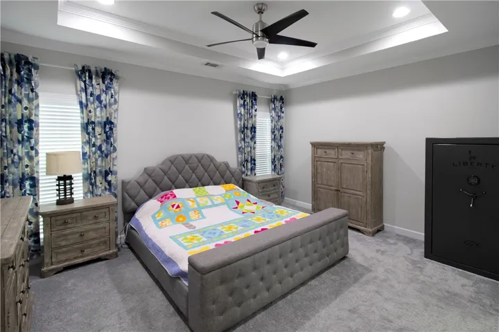 This restful bedroom features a tray ceiling and soft carpet, perfect for peaceful nights.