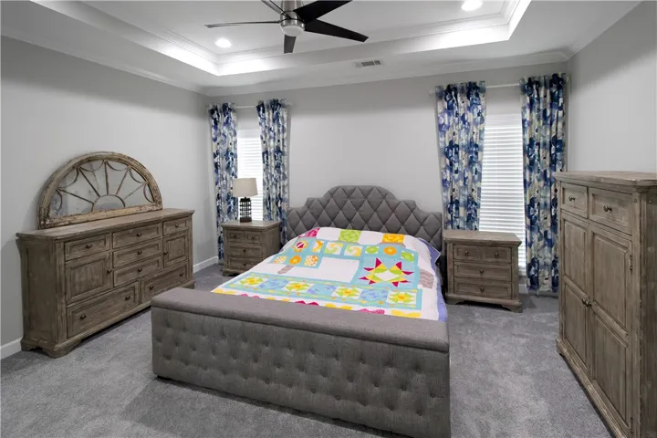 This tranquil bedroom features plush carpeting and elegant tray ceilings, perfect for unwinding.