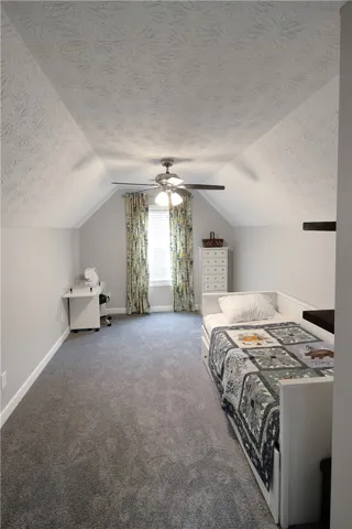 This inviting bedroom features vaulted ceilings and plush carpet flooring, offering a comfortable personal retreat.