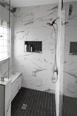 This modern bathroom features a spacious shower with intricate tile work and convenient recessed shelving.