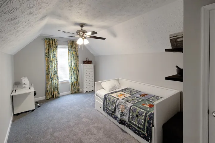 This cozy bedroom features sloped ceilings and ample natural light, perfect for relaxation or a creative workspace.