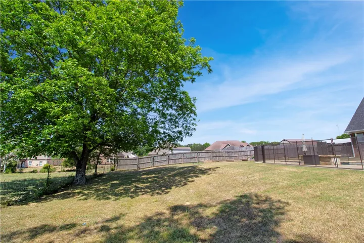 This spacious yard features mature trees and a fenced pool area for recreation.