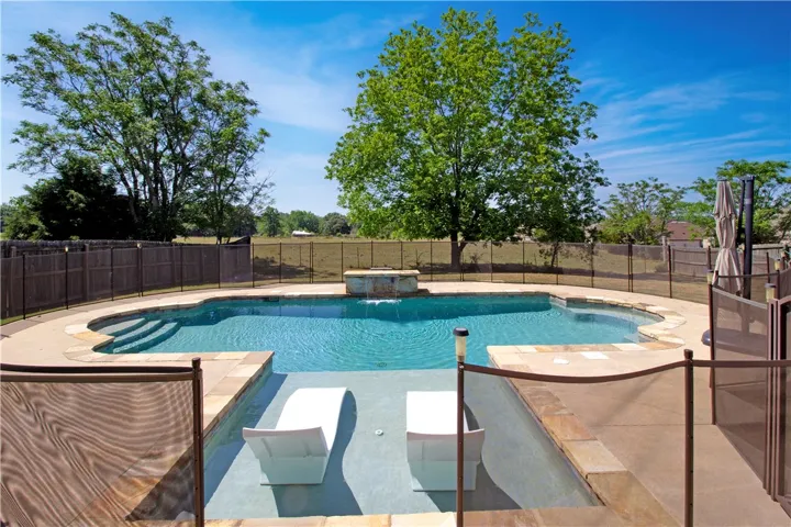 An inviting backyard oasis features a glistening pool with ample space for lounging and recreation.