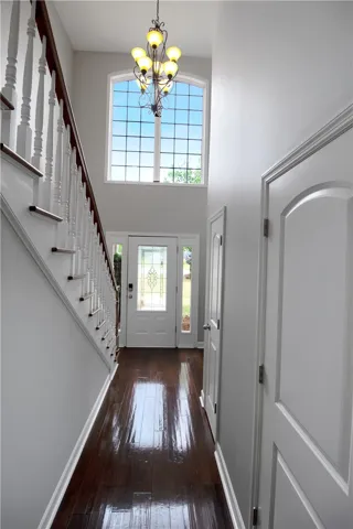 This entry hall features rich wood flooring, a staircase, and a large window above the main entry.