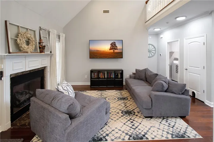 This inviting living area boasts high ceilings, a fireplace, and hardwood flooring, perfect for relaxation.