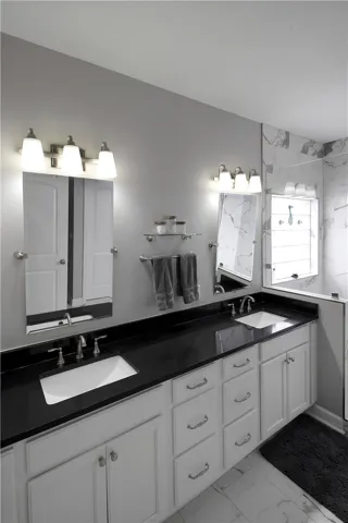 This spacious bathroom features double vanities and a contemporary walk-in shower.