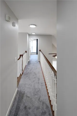 This spacious hallway features elegant wooden banisters and plush carpet flooring.