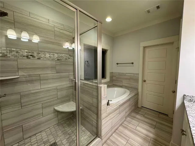 This bathroom features a sleek glass shower and a luxurious soaking tub for ultimate relaxation.