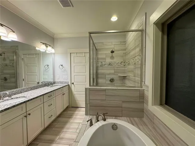 This spacious bathroom offers a relaxing soaking tub and a sleek, modern walk-in shower.