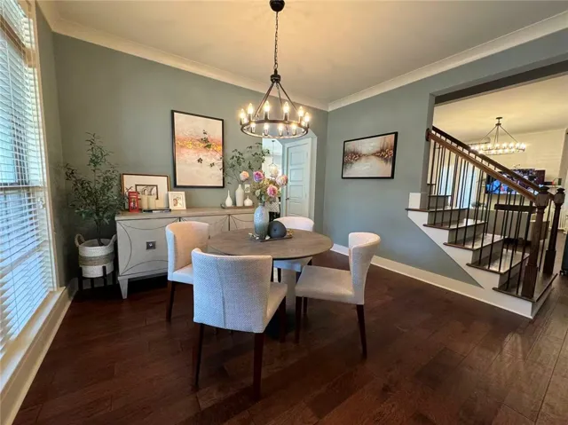 Elegant dining space featuring rich wood flooring and a classic staircase.