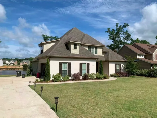 This charming residence features a well-maintained lawn and a serene lakeside setting.