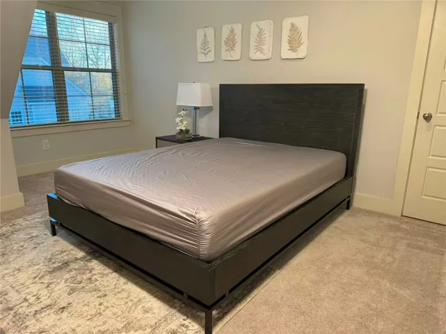 This inviting bedroom features plush carpeting and abundant natural light, offering a comfortable personal retreat.