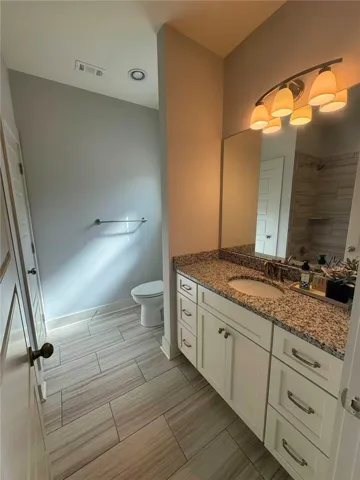 This bright bathroom offers a sleek vanity with ample storage and contemporary fixtures.