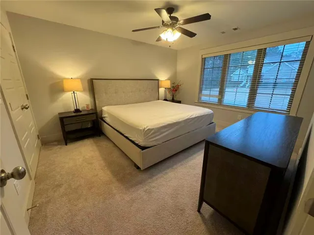 This restful bedroom offers carpet flooring and a ceiling fan for optimal comfort.