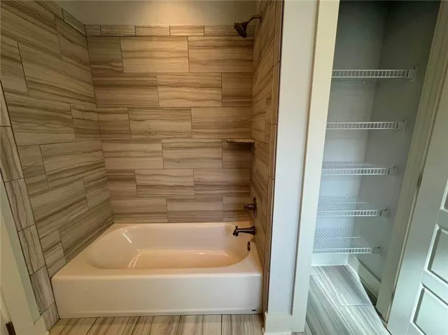 This bathroom features a sleek tiled shower with an integrated shelf and convenient wire shelving storage.