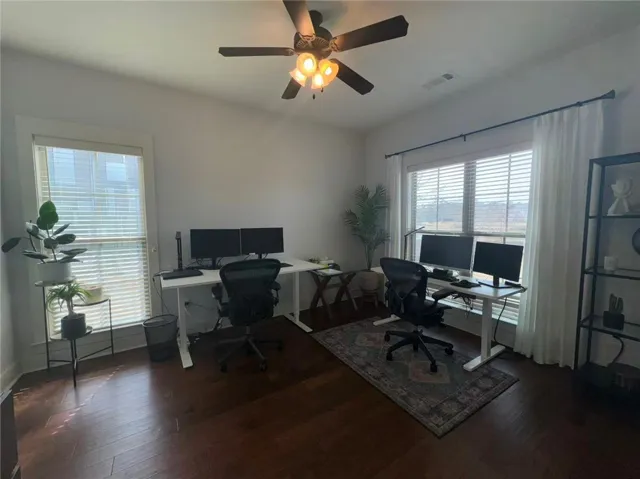 This dedicated office space features rich wood flooring, ample natural light, and a functional overhead fan for comfort.