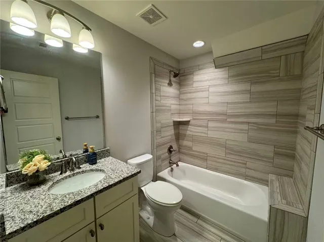 This sleek bathroom features a modern vanity with granite counters and a clean, tiled shower and tub.