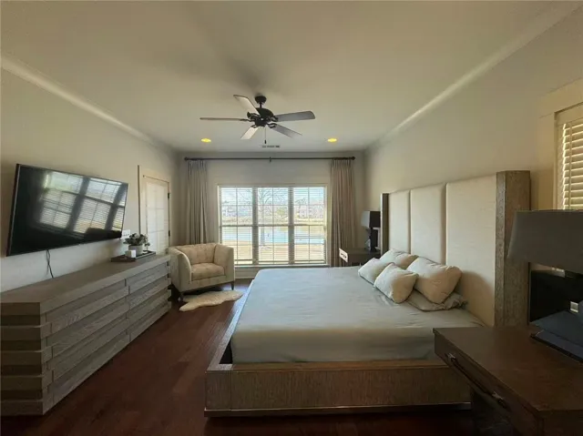 This inviting bedroom features rich hardwood flooring and a serene view of the lake.