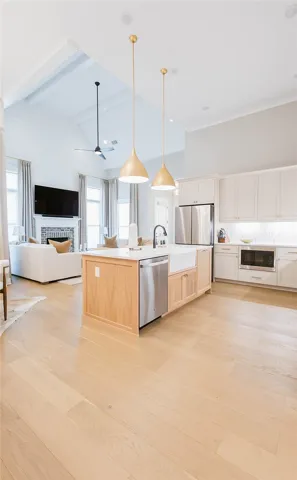 This bright, open-concept interior features elegant hardwood flooring, high ceilings, and an inviting fireplace.