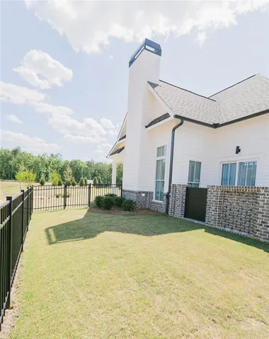 This residence features a crisp white exterior with a contrasting dark roof and chimney, surrounded by green.