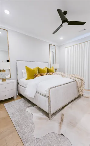 This primary bedroom features elegant wood flooring, recessed lighting, and a ceiling fan for ultimate comfort.
