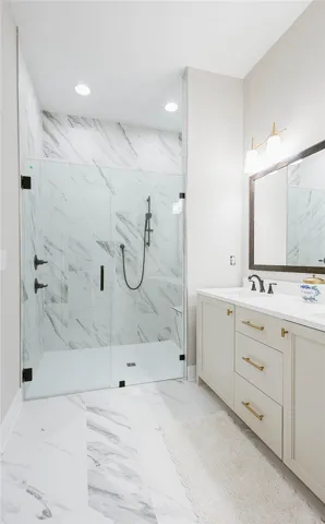This clean and bright bathroom features elegant marble flooring and a spacious walk-in shower.