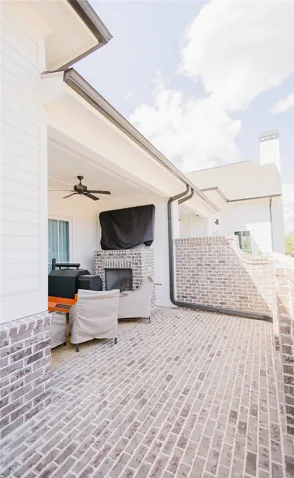 This inviting outdoor space features a fireplace and a durable brick patio.